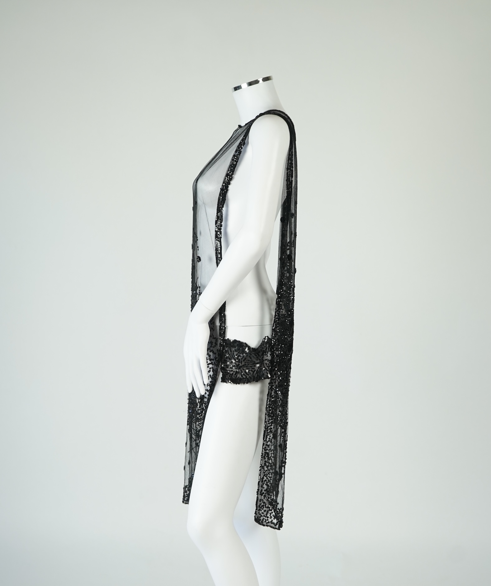 A 1920's black sequin on net tabard, with floral decoration and two side sequinned straps. Length 97cm. Condition - a few sequins have detached but are in a bag for re-attaching.